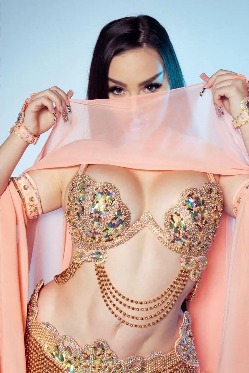 Belly dancer BI holding a peach veil over her face