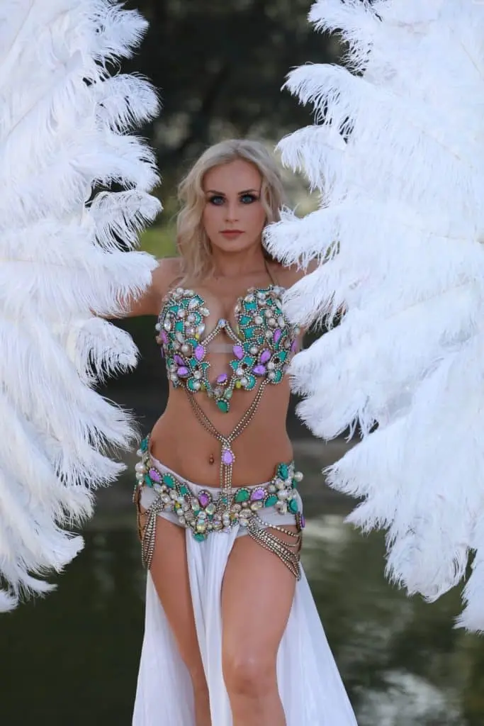 Belly dancer in a jewelled costume with large white feather fans