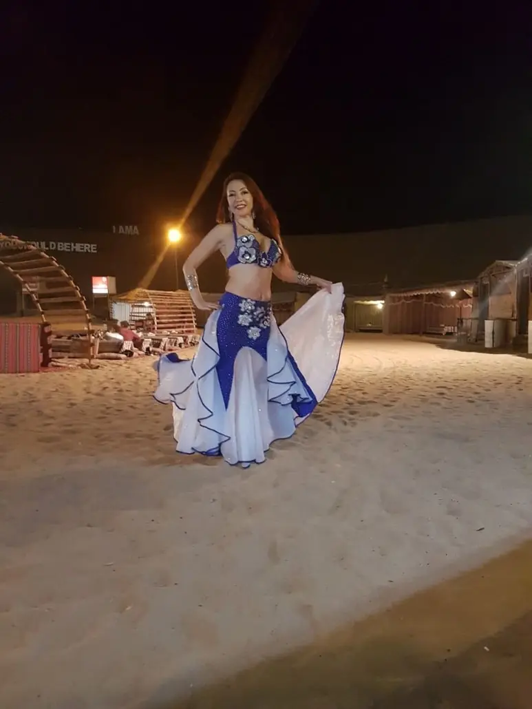Belly dancer M performing on the sand at a desert camp at night