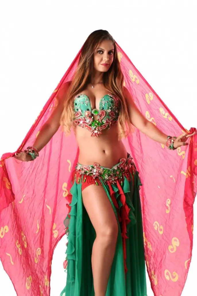 Belly dancer R spreading a pink veil over a green and red costume