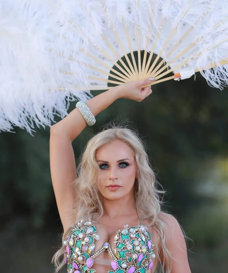 Belly dancer V with a white feather fan by the water