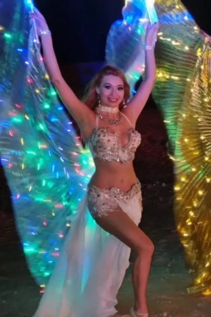 Belly dancer with glowing LED wings at a night show