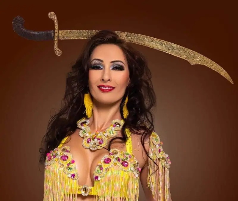 Eve, belly dancer, holding a sword above her head