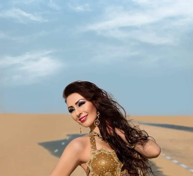 Eve, belly dancer, in a gold costume in the desert