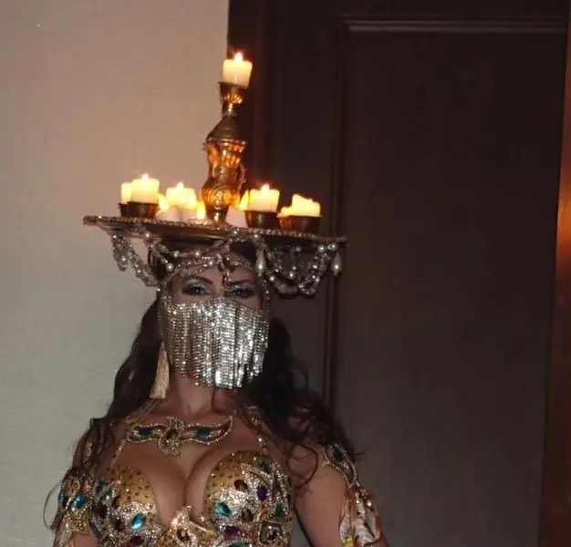 Eve, belly dancer, with a candle tray on her head and a jewelled face veil