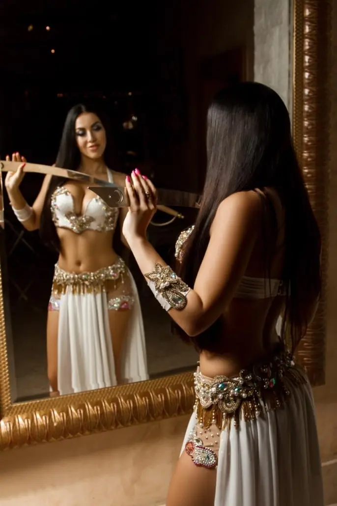 Maria, belly dancer, holding a sword in front of a mirror