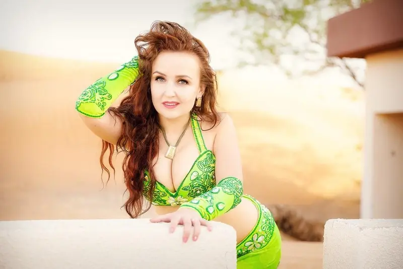 Omira, belly dancer, in a green costume outdoors